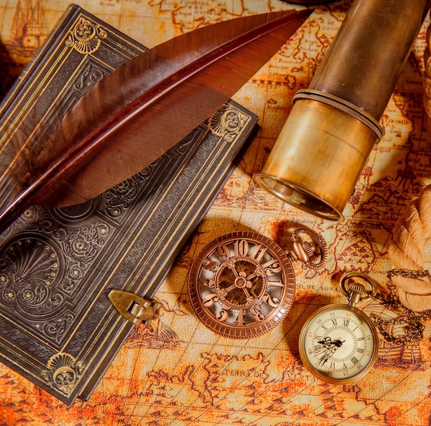 Ainda vida vintage - lupa, relógio de bolso, livro antigo e caneta de pena de ganso em um mapa antigo em 1565.