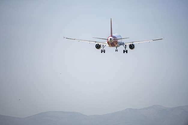 Un Airbus A321 se acerca a la pista para aterrizar en un aeropuerto con montañas en el fondo