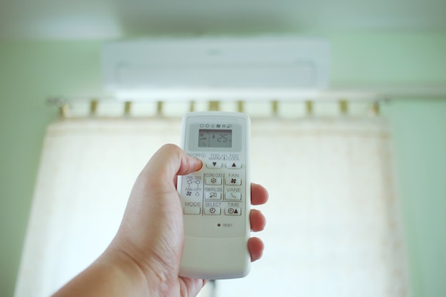 Foto aire acondicionado dentro de la habitación con el hombre abre o cierra el control remoto.