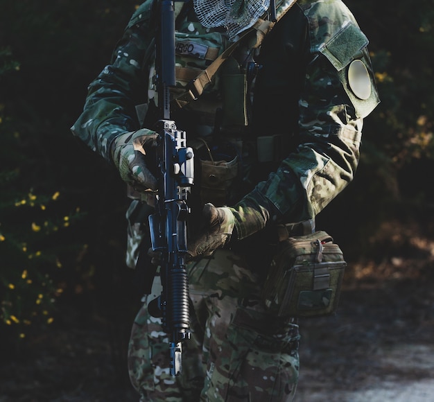 Airsoft-Militärspieler in Tarnuniform mit bewaffnetem Sturmgewehr.