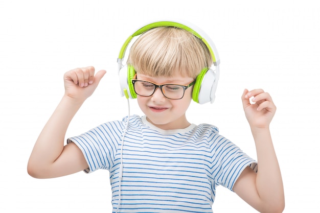 Aislado en blanco niño lindo escuchando la música en los auriculares. Niño sobre fondo blanco con auriculares.