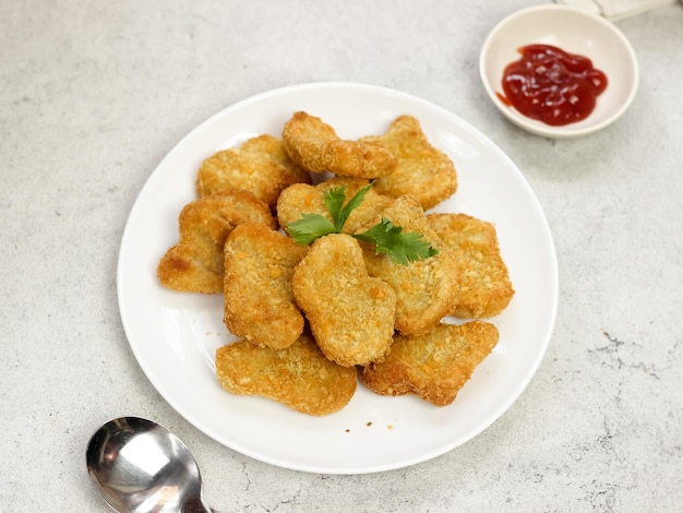 Aislado un plato de nuggets de pollo servidos con salsas de tomate sobre fondo blanco.