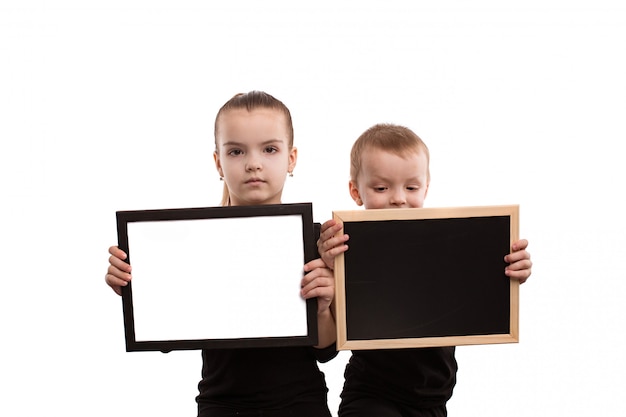 Foto aislados en fondo blanco niño y niña en camisetas negras muestran formularios en blanco