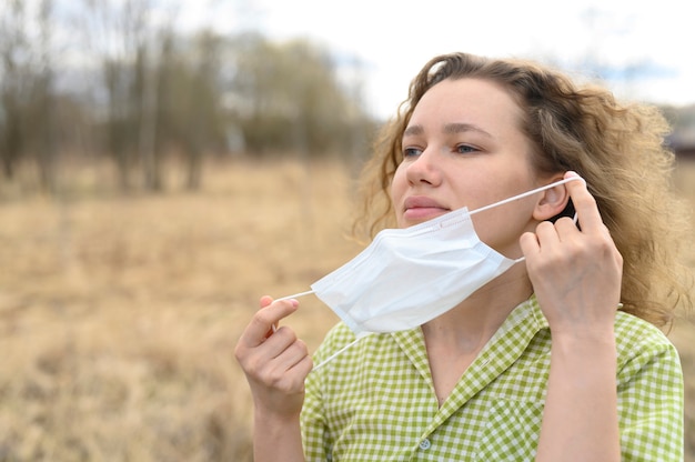 El aislamiento final y el concepto de cuarentena del virus corona covid-19. joven europea se quitó una máscara médica de la cara y respira aire fresco en la naturaleza al aire libre