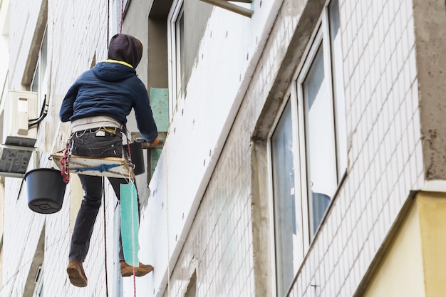 Aislamiento térmico del panel de pared exterior. El hombre trabajador aísla la pared del edificio de gran altura