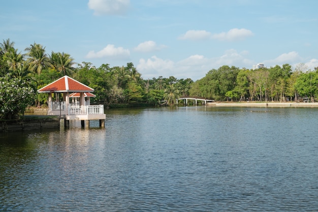 Ajardine a vista de um lago e pavilhões da margem com floresta.