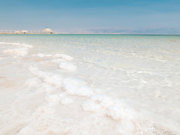 Ajardine a vista sobre as formações dos cristais de sal do Mar Morto limpam a água verde ciano na praia Israel de Ein Bokek