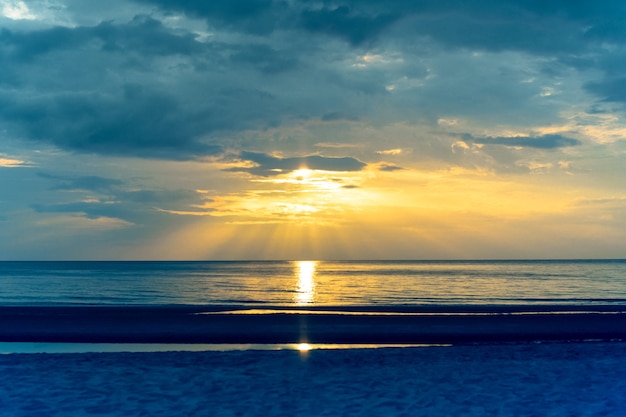 Ajardine la puesta del sol en la playa con la llamarada ligera en el océano en color de proceso cruzado.