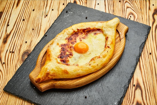 Ajarian Khachapuri pastel de queso georgiano tradicional con huevos en una tabla de cortar Horneado casero Pastel abierto con mozzarella