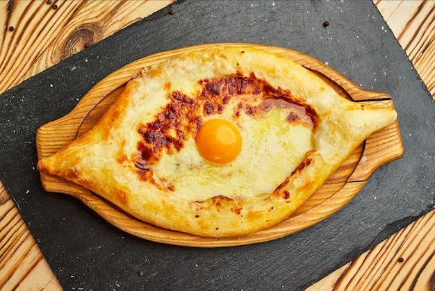 Foto ajarian khachapuri pastel de queso georgiano tradicional con huevos en una tabla de cortar horneado casero pastel abierto con mozzarella