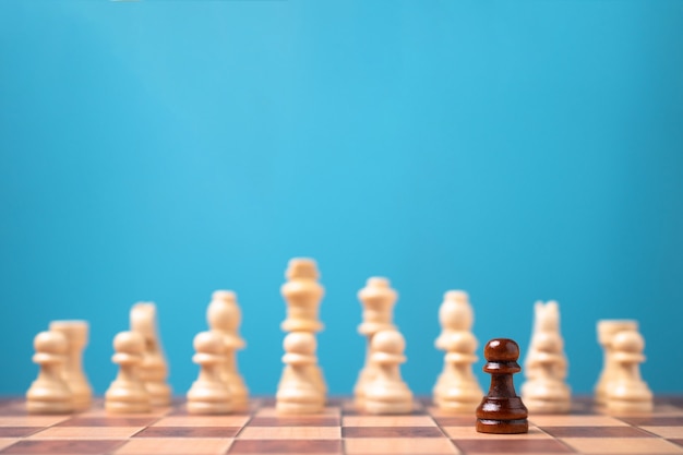 Ajedrez marrón de pie delante del ajedrez blanco, concepto de desafío en la competencia