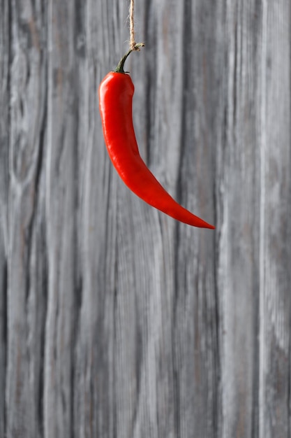 Ají rojo colgado sobre un fondo de madera gris y espacio para el texto Primer plano