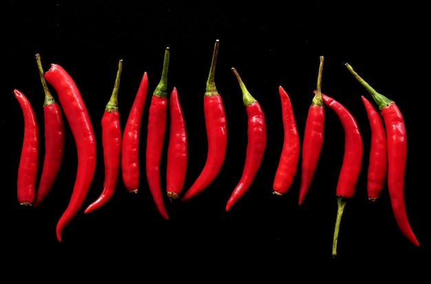 Foto ají rojo en horquilla de madera sobre fondo negro