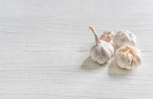 Ajo orgánico entero y clavos en fondo de madera.