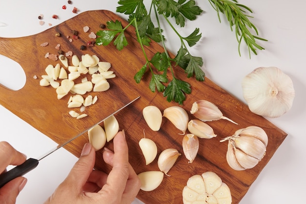 Ajo con romero, perejil y pimienta sobre una tabla de madera aislada sobre superficie blanca. Vista superior. Endecha plana. Recién recogido del huerto orgánico de crecimiento doméstico. Concepto de comida.