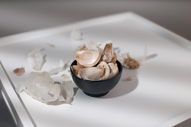 Ajo en tazón negro sobre una mesa de madera blanca