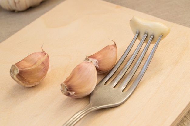 Ajo con un tenedor en la tabla de cortar, primer plano