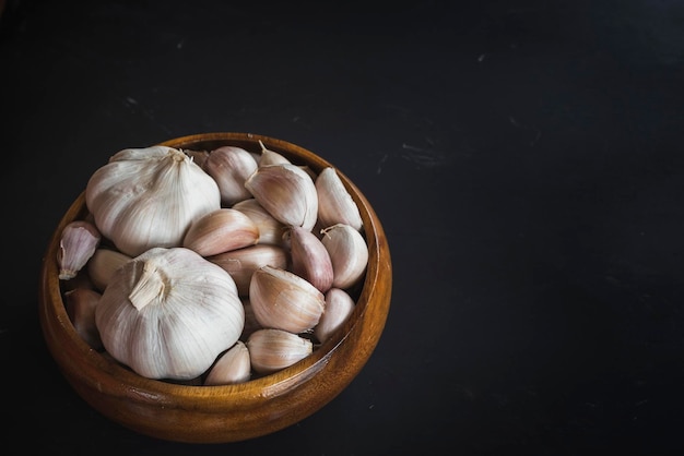 Foto ajos en bolw de madera sobre fondo de tablones de madera negros componentes de alimentos no frescos y muy secosfoto macro de alimentos