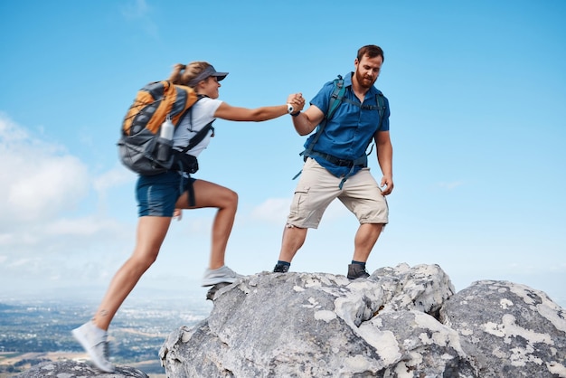 Ajudando o casal a escalar ou caminhar montanha na natureza em férias ou viagem Apoio de resgate de liberdade e homem e mulher viajando ao ar livre no exercício ou treino de escalada rural