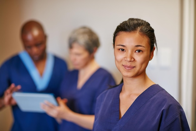 Foto ajudar as pessoas é tão gratificante retrato recortado de uma enfermeira em um hospital com seus colegas ao fundo