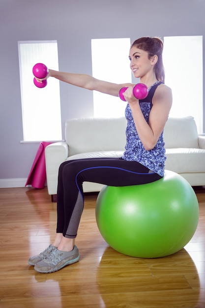 Foto ajude a mulher a levantar dumbbells na bola de exercício