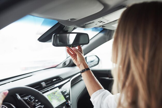 Foto ajustando o espelho retrovisor vista de perto das mãos da mulher no belo carro moderno de cor preta