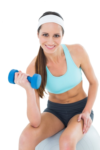 Ajustar a mulher exercitando com dumbbell na bola de fitness