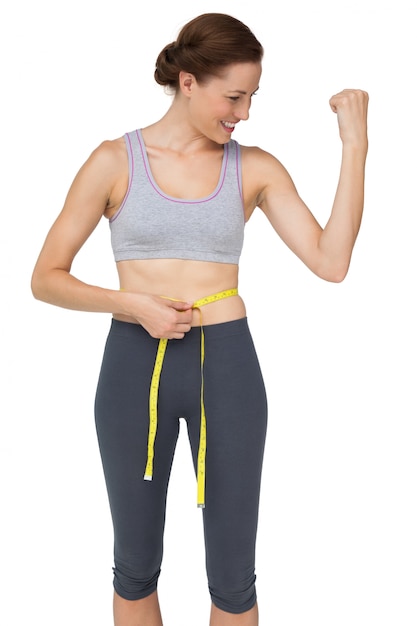Ajustar a mulher medindo a cintura enquanto flexiona os músculos