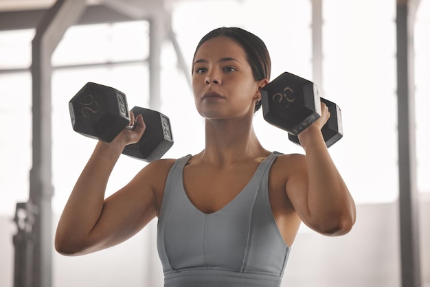 Ajuste atleta activo y fuerte haciendo entrenamiento muscular del brazo y ejercicios con pesas o pesas en un gimnasio para un estilo de vida de bienestar Primer plano de una mujer deportiva haciendo ejercicios de fuerza y resistencia