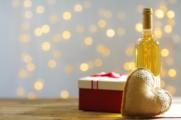 Ajuste de una botella de vino, un regalo en la caja y otra decoración, sobre fondo borroso