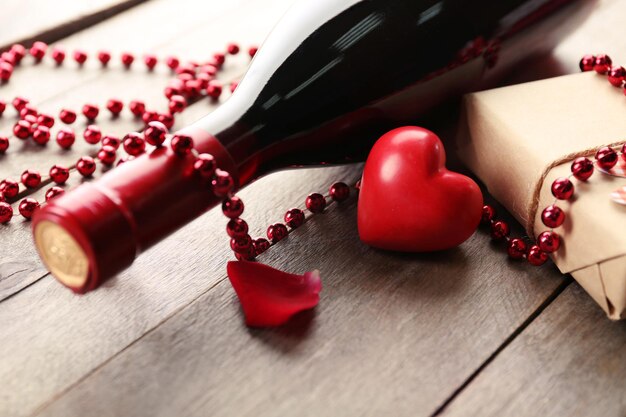 Foto ajuste de una botella de vino, un regalo en la caja y otra decoración, sobre fondo de madera