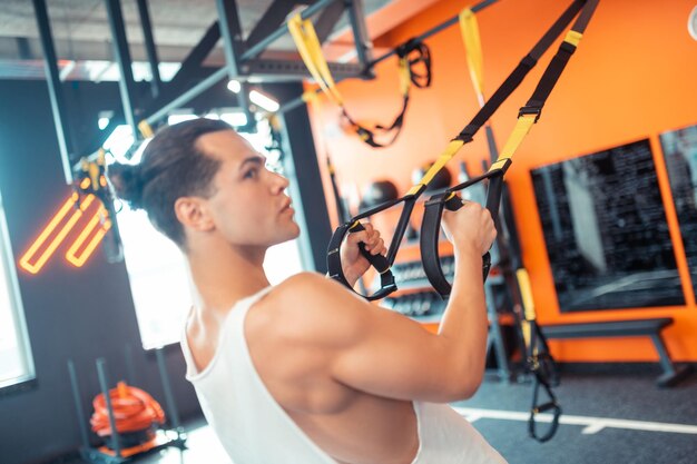 Ajuste buen mozo haciendo un ejercicio con correas de fitness