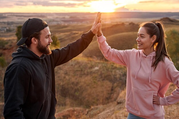 Ajuste Casal de atletas dando mais cinco para comemorar os objetivos e o sucesso do treino ao ar livre.