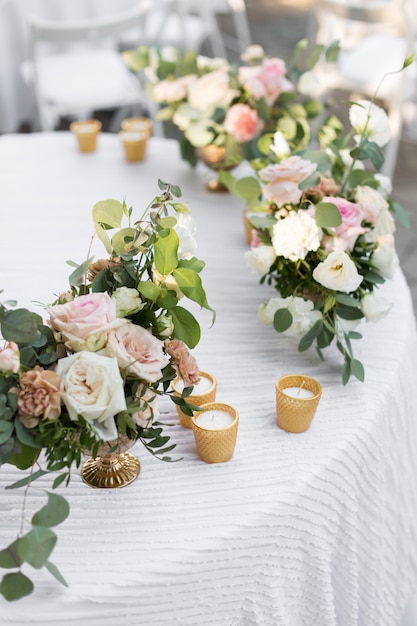 Ajuste da tabela do casamento decorado com flores frescas em um vaso de bronze. Floricultura casamento