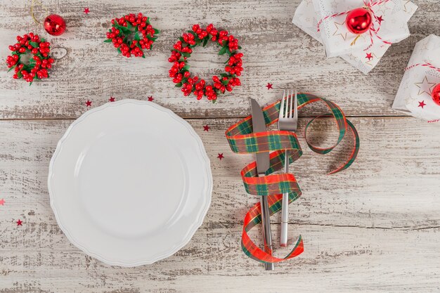 Ajuste de lugar de inverno com decorações de natal e ano novo na mesa de madeira branca. configuração de mesa festiva para o jantar de natal. postura plana