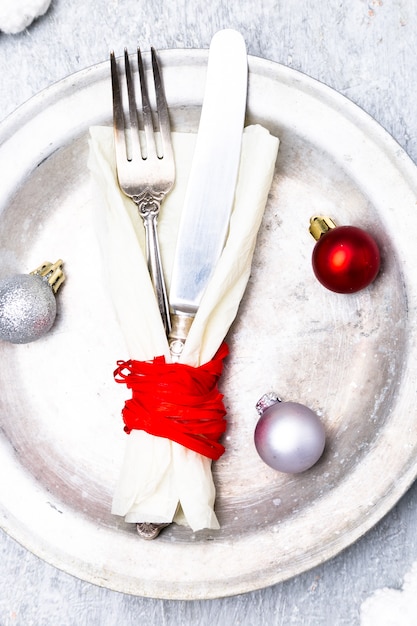 Ajuste de lugar de mesa de natal. fundo de férias. placa de prata, faca e garfo com decorações de natal. vista do topo.