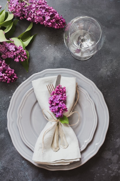 Ajuste de lugar elegante da tabela da mola com lilás violeta, pratas na tabela do vintage.