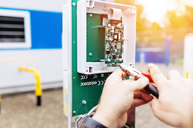 Ajuste de equipos de control y medición Las manos de un electricista o ingeniero con alicates en el primer plano de trabajo