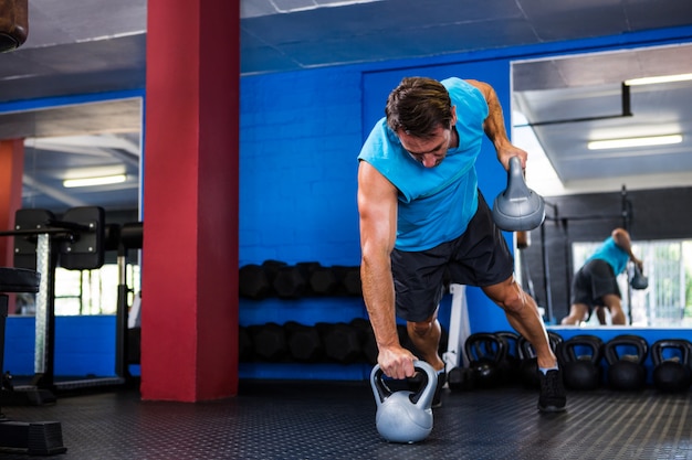 Ajuste joven sosteniendo pesas rusas en el gimnasio