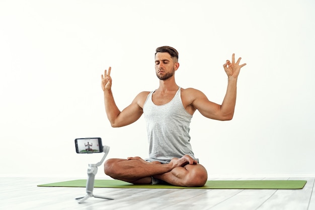 Ajuste macho caucásico grabando un blog o haciendo ejercicio de yoga en tiempo real