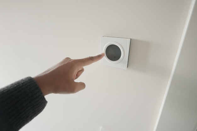 Ajuste manual del termostato inteligente en la pared blanca para un control óptimo de la temperatura en el hogar