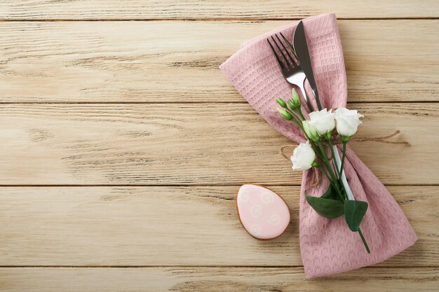 Ajuste de la mesa de brunch de Pascua Concepto de vacaciones de Pascua de primavera con plato rosa blanco y servilleta con símbolos decorativos huevos de conejo de vacaciones y ramo de flores sobre fondo de madera vieja Vista superior