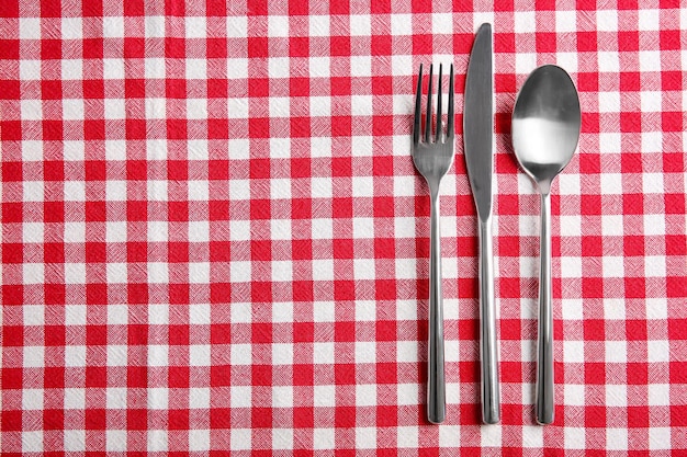 Ajuste de la mesa con cubiertos de plata en servilleta de tablero de ajedrez