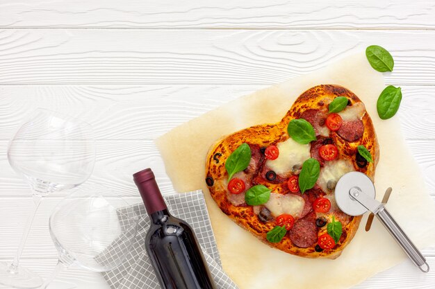 Ajuste de la mesa del día de San Valentín. Pizza de corazón con vino