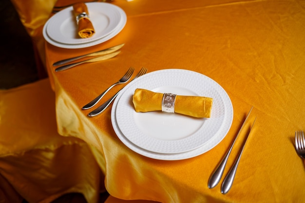 Ajuste de la mesa elegante con tenedor, cuchillo y servilleta de oro