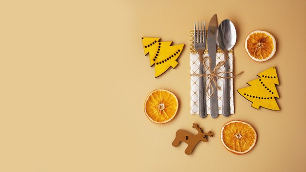 Ajuste de la mesa con estatuillas navideñas de madera y naranja seca sobre fondo dorado - vista superior