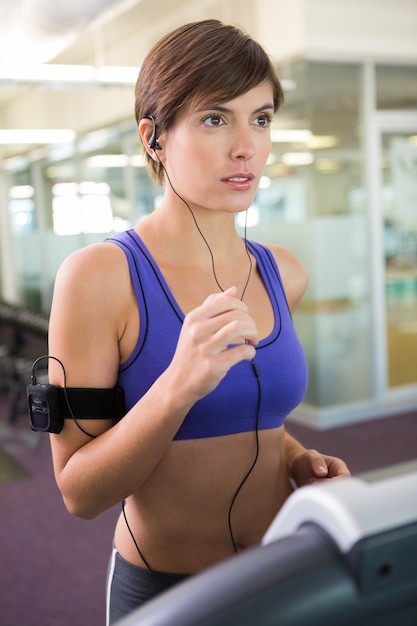 Ajuste morena corriendo en la cinta escuchando música