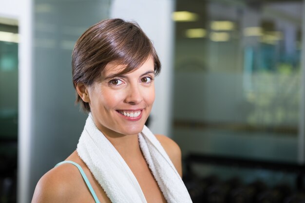 Ajuste morena sonriendo a la cámara con una toalla alrededor de los hombros