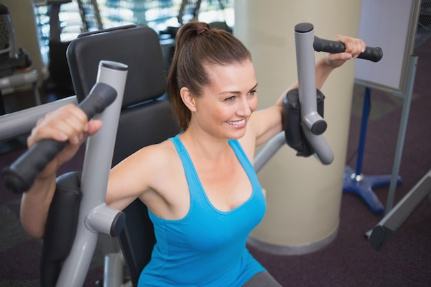 Ajuste morena usando la máquina de pesas para brazos en el gimnasio