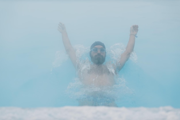 Ajuste nadador entrenamiento masculino nadar en piscina abierta de invierno con niebla Concepto de spa geotérmico al aire libre